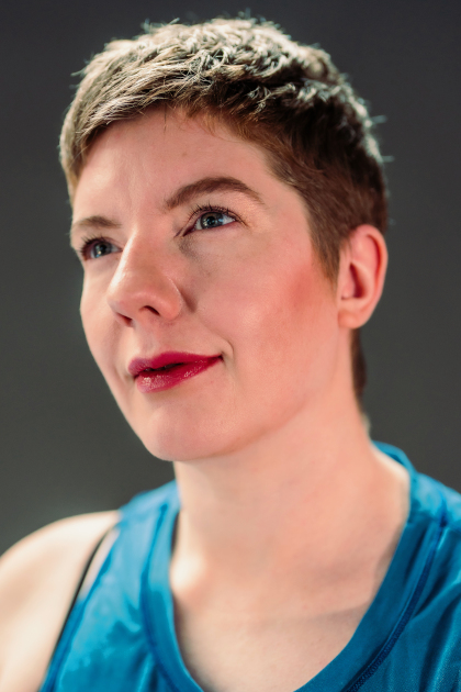 
	Laurel Lawson headshot. A white person with short cropped hair, chin lifted and gaze directed upwards with a slight smile; blue eyes echo a blue gauze tank. Photo Robbie Sweeny
		